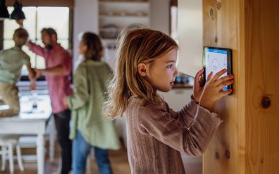 Girl looking at the smart thermostat at home, checking heating temperature. Concept of sustainable, efficient, and smart technology in home heating and thermostats.